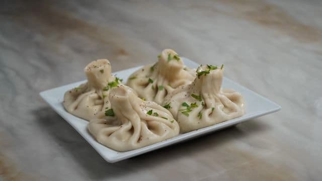Handmade Georgian Khinkali dumplings on a plate, ready to be enjoyed, showcasing the intricate folds of the traditional Georgian khinkali.