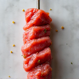 High-quality image of perfectly grilled pork shashlik on skewers, showing the rich, caramelized exterior and juicy texture. The skewers are artfully arranged, highlighting the traditional Armenian Khorovats cooking method. The image captures the inviting aroma and delicious presentation of this classic dish.